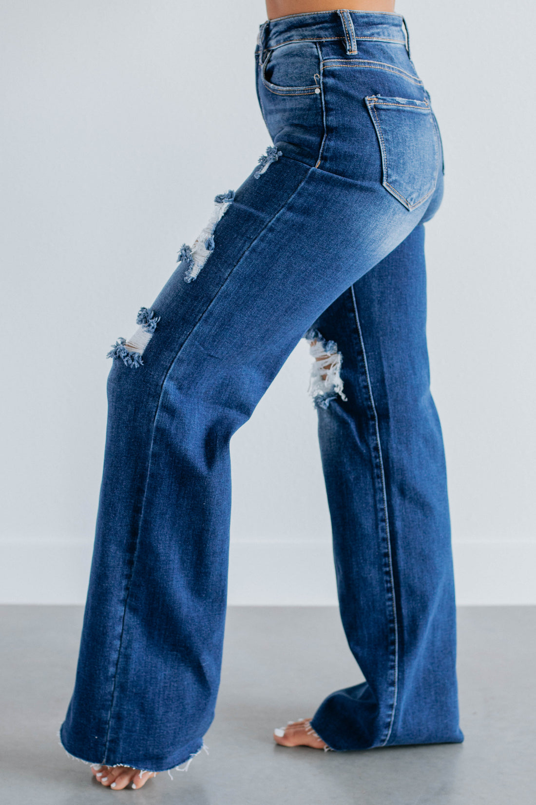 Blue jeans with distressed details on a plain background